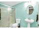 Bathroom with blue walls, pedestal sink, toilet, and a glass shower door with metal trim at 1808 Woodfield Dr, Greenwood, IN 46143