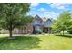Charming two-story brick home with a well-manicured lawn and mature trees on a sunny day at 1808 Woodfield Dr, Greenwood, IN 46143