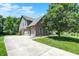 Three car garage with a brick exterior, a driveway, landscaping and mature trees providing shade and beauty at 1808 Woodfield Dr, Greenwood, IN 46143