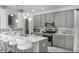 Modern kitchen featuring gray cabinets, quartz countertops, stainless steel appliances, and an island with bar seating at 210 Lynnette Way, Cumberland, IN 46229
