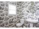 Charming bathroom showcases unique toile wallpaper, pedestal sink, and ample natural light at 47 Torrey Pine Dr, Brownsburg, IN 46112