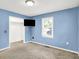 Blue bedroom featuring plush carpet, a mounted TV, and closet space at 6616 S Cross St, Pendleton, IN 46064