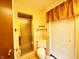 Bathroom featuring a shower with gold trim, white toilet and window with blinds at 7038 E 65Th St, Indianapolis, IN 46256