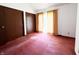 Spacious bedroom featuring red carpet, closet door, and curtains over windows at 7038 E 65Th St, Indianapolis, IN 46256