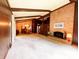 Open-concept living room and dining area featuring a brick fireplace, wood paneling, and plush carpeting at 7038 E 65Th St, Indianapolis, IN 46256