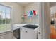 Bright laundry room featuring a modern washer and dryer, a window, and shelf space at 7356 Woodington Pl, Indianapolis, IN 46259