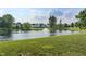 Scenic pond with a fountain surrounded by green grass and neighborhood homes in the distance at 7356 Woodington Pl, Indianapolis, IN 46259
