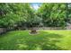 Landscaped backyard with lush green grass, trees, and fire pit at 7720 Langwood Dr, Indianapolis, IN 46268