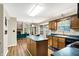 A kitchen featuring wood cabinets, an island with a teal countertop, and views of the living room's brick fireplace at 7720 Langwood Dr, Indianapolis, IN 46268