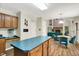 An open kitchen showcases wood cabinets, a center island with teal counters, and an adjacent breakfast nook overlooking the living room at 7720 Langwood Dr, Indianapolis, IN 46268
