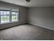 Spacious bedroom featuring neutral walls, plush carpet, and a pair of bright windows with neighborhood views at 8415 Fieldfare Way, Indianapolis, IN 46237