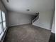 Open concept living room with plush carpeting, bright natural light, and a staircase to the upper level at 8415 Fieldfare Way, Indianapolis, IN 46237