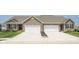 Two-unit home with brick facade, white garage doors, well-maintained lawns, and concrete driveways at 8842 Twain Ln, Indianapolis, IN 46239