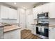 Well-lit kitchen boasts white cabinetry, stainless steel appliances, and wood-look flooring at 8842 Twain Ln, Indianapolis, IN 46239