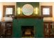 Close up of fireplace with green tiles, custom cabinets, and period lighting at 972 N Audubon Rd, Indianapolis, IN 46219