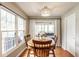 Sunny dining area with a round table, wood chairs, hardwood floors, and large windows with white curtains at 9740 Logan Ln, Fishers, IN 46037