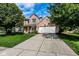 Traditional brick home with a well-manicured lawn, long driveway, and mature trees under a blue sky at 9740 Logan Ln, Fishers, IN 46037