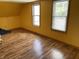 Bright bedroom with two windows offering ample natural light, complemented by wood-look flooring and yellow walls at 1163 Groff Ave, Indianapolis, IN 46222