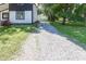Charming home featuring white siding, black trim, a gravel driveway, and a spacious yard with mature trees at 12003 Broadway St, Indianapolis, IN 46236