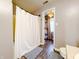 Bright bathroom showing a shower with white curtain and view of a storage area with hanging light at 1242 Flatrock Dr, Anderson, IN 46013