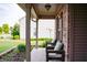 Inviting front porch with brick detail, porch chairs, and view of front yard at 1242 Flatrock Dr, Anderson, IN 46013