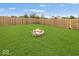 Lush backyard featuring a stone fire pit, surrounded by green grass and a privacy fence at 12845 Touchdown Dr, Fishers, IN 46037