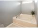 Brightly-lit bathtub featuring clean white walls, neutral tile, and small plant for decor at 12845 Touchdown Dr, Fishers, IN 46037