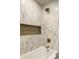 Close-up of a modern bathtub with a tiled surround, built-in niche, and bronze fixtures at 130 N High School Rd, Indianapolis, IN 46214