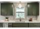 Bright kitchen with green cabinets, quartz countertops, modern hardware, and stylish backsplash tile at 130 N High School Rd, Indianapolis, IN 46214