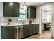 A charming kitchen showcases trendy green cabinets, stainless steel appliances, and a view to the laundry at 130 N High School Rd, Indianapolis, IN 46214