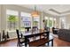 A dining room has hardwood floors, large windows, a modern chandelier, and a wood dining table with seating at 1457 Birdsong Dr, Westfield, IN 46074