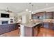 A kitchen with dark wood cabinets, granite counters, stainless appliances, and center island flows into the living room at 1457 Birdsong Dr, Westfield, IN 46074