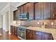A kitchen features granite counters, backsplash, stainless microwave, cooktop, oven, and dark wood cabinets at 1457 Birdsong Dr, Westfield, IN 46074
