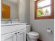 Stylish bathroom with a white vanity, modern sink and faucet, matching toilet, and a window with natural light at 15120 Romalong Ln, Carmel, IN 46032