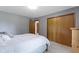 Bedroom with gray walls, carpeted floors, closet with wooden sliding doors, and neutral bedding at 15120 Romalong Ln, Carmel, IN 46032