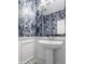 A half bathroom boasts pedestal sink, chrome fixtures, wainscoting, and eye-catching marble-patterned wallpaper at 16310 Nightshore Ln, Fishers, IN 46037