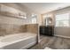 Modern bathroom featuring a soaking tub, dark vanity, decorative wall art, and updated fixtures at 16310 Nightshore Ln, Fishers, IN 46037