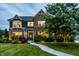 Charming two-story brick home with a well-manicured lawn and lush landscaping at dusk at 16310 Nightshore Ln, Fishers, IN 46037
