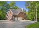 Brick house with a three-car garage and driveway, surrounded by lush greenery and mature trees at 2034 Dynasty Ridge Rd, Martinsville, IN 46151