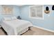 Light blue bedroom with a plush white bed, window, and decorative wall art at 2715 Benmore Ct, Zionsville, IN 46077