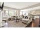 Open-concept living room featuring a plush sectional sofa, large windows, and a seamless transition to the kitchen at 2715 Benmore Ct, Zionsville, IN 46077