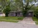 View of exterior, highlighting the home's setting amongst trees and a driveway, in a residential neighborhood at 3509 N Wittfield St, Indianapolis, IN 46235