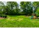 Spacious backyard with a playset, lush green lawn, and mature trees at 3715 Rolling Springs Dr, Carmel, IN 46033
