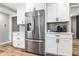 Spacious kitchen featuring stainless steel refrigerator, pristine white cabinetry, and wood-look laminate flooring at 3715 Rolling Springs Dr, Carmel, IN 46033