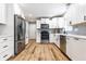 Bright kitchen boasts stainless steel appliances, sleek white cabinets, and wood-look floors for a modern feel at 3715 Rolling Springs Dr, Carmel, IN 46033
