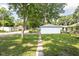 Spacious backyard featuring a detached white garage with a quaint pathway leading up to it, shaded by mature trees at 4502 Evanston Ave, Indianapolis, IN 46205