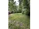 Backyard featuring a grassy lot, mature trees, and a red car in the driveway at 4744 E 33Rd St, Indianapolis, IN 46218