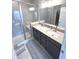 Modern bathroom with a double vanity, a glass shower door, neutral tile, and sleek fixtures at 5103 Covington Ave, McCordsville, IN 46055