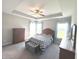 Spacious main bedroom with a tray ceiling, a ceiling fan, a bed, a dresser, and natural light from the windows at 5103 Covington Ave, McCordsville, IN 46055