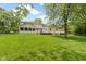 Spacious backyard with a large deck, lush green lawn, mature trees, and an enclosed sunroom attached to the house at 59 Sycamore Dr, Carmel, IN 46033